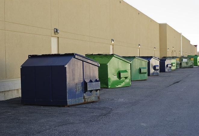 construction workers throw waste into a dumpster behind a building in Felda